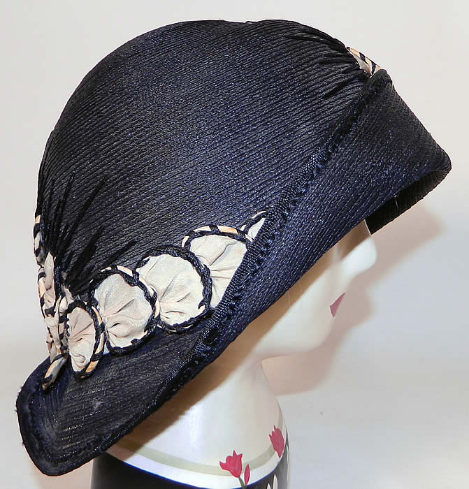 Vintage Black Straw Upturned Brim White Silk Flower Flapper Cloche Hat. It is made of a black tightly woven straw, with white silk rosette flower applique trim outlined in black stitching.