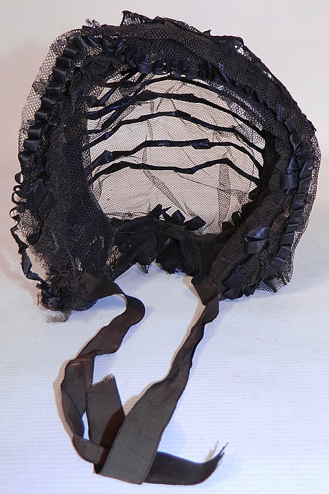 Victorian Civil War Era Black Net Ribbon Trim Mourning Bonnet Snood Headdress. The bonnet measures 17 inches around the front face and is 12 inches deep from front to back. It is in good condition, with only some slight fraying of the silk ties at the chin. This is truly a wonderful rare piece of antique mourning millinery art!