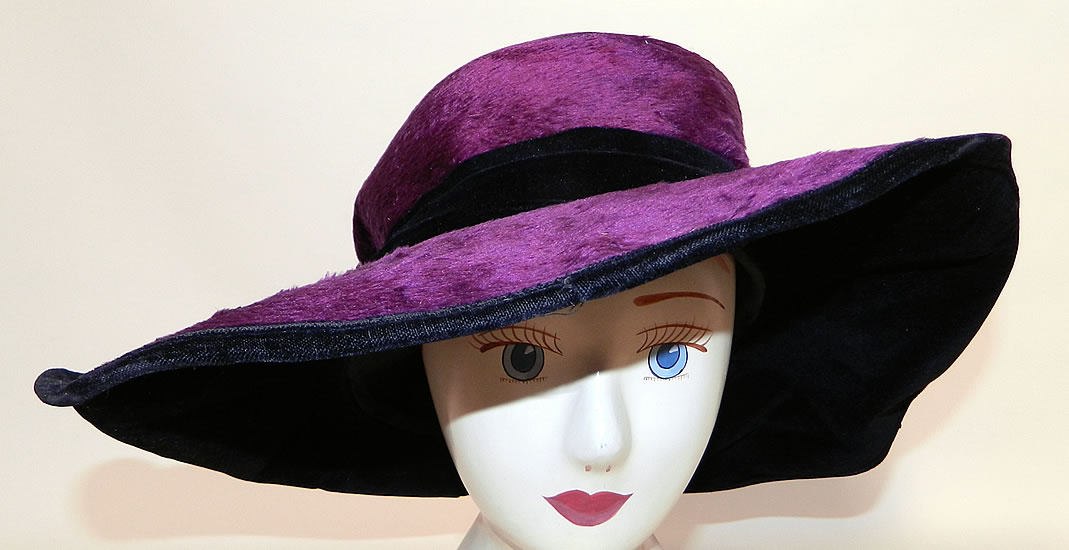 Edwardian Vintage Wolf Millinery Purple Velvet Flower Trim Wide Brim Hat. It is made of a dark purple plum plush silk velvet fabric, with a black velvet ribbon hatband, purple and orange wired pipe cleaner chenille flower trim decorating the sides.