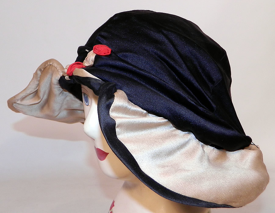 Vintage Art Deco Black & White Silk Red Rosette Wired Wing Brim Flapper Cloche Hat. It is made of a black and off white cream color silk fabric, with red and white silk rosette flower trim around the crown. 