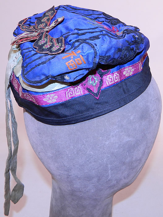 Antique Chinese Child Infant Silk Embroidered Butterfly Wind Hat Cap
This antique Chinese child infant silk embroidered butterfly wind hat cap dates from the 1920s. It is hand stitched, made of a blue silk fabric, with black soutache braided embroidery work and purple silk damask brocade ribbon trim. 
