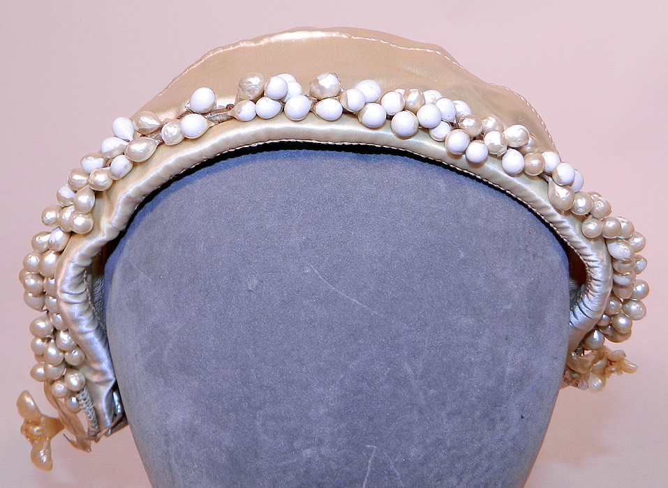 Vintage White Satin Bridal Wedding Cap Orange Blossom Wax Flower Trim
It is made of an off white cream color satin fabric cap, with pearl iridescent covered wax orange blossom flower droplets sewn around the front opening and is net lined inside. This beautiful bridal bonnet wedding cap measures 22 inches in circumference. 