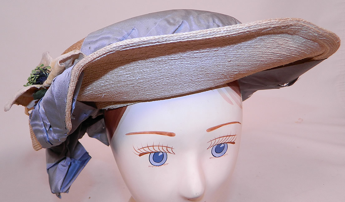 Victorian White Woven Straw Blue Silk Ribbon Floral Trim Wide Brim Gainsborough Hat
This antique Victorian era white woven straw blue silk ribbon floral trim wide brim Gainsborough hat dates from 1890. It is made of a woven white natural straw, with a cornflower blue color silk moire ribbon and cream velvet flower trim.
