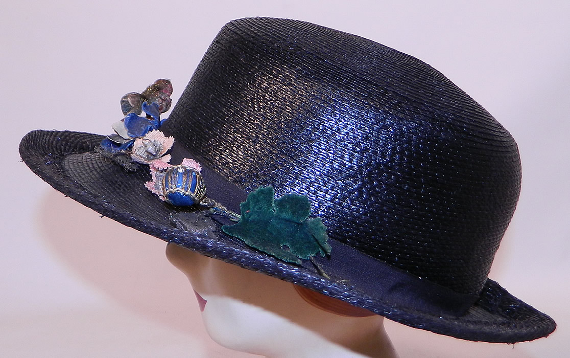 Edwardian Belle Epoque Woven Black Straw Gold Metallic Floral Trim Wide Brim Hat
This beautiful Belle Epoque straw boater style hat has an uneven asymmetrical oval shape wide brim, which is wider along the sides and front, a tall round crown and is unlined. 
