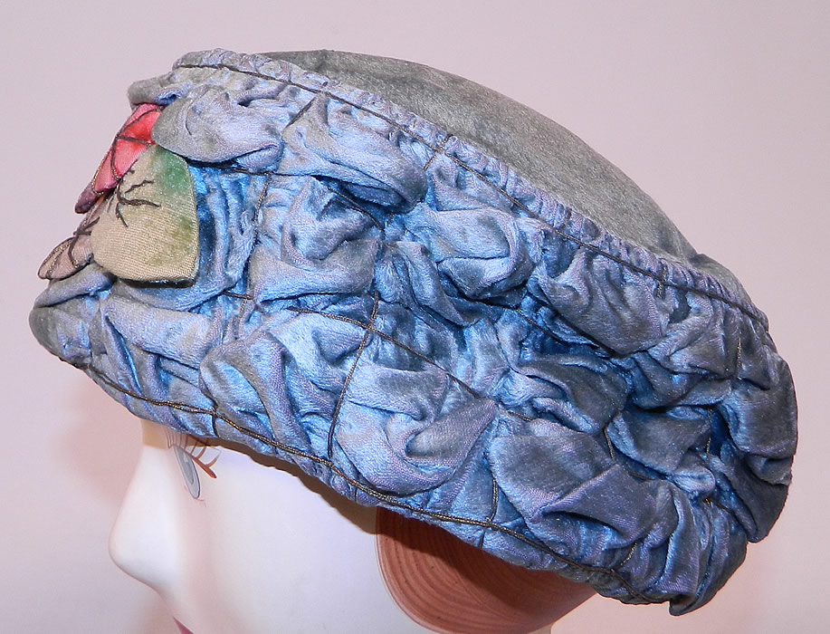 Vintage Ruched Cornflower Blue Gray Velvet Silver Lame Leaf Trim Toque Cloche Hat Lam&eacute;
The hat is made of a cornflower blue gray color velvet fabric with ruched tucks gathering, silver lam&eacute; thread binding and colorful velvet leaf trim on the front. 