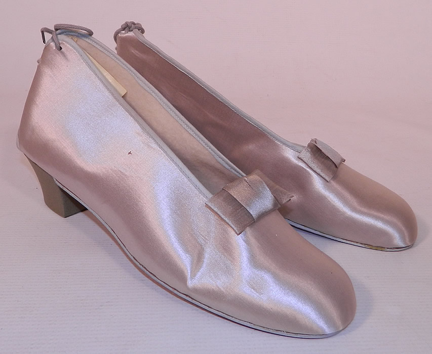 Vintage Practical Burial Slippers Silver Grey Satin Funeral Shoes Pumps. They are made of a silver grey satin fabric with decorative bow trim on the front vamps.