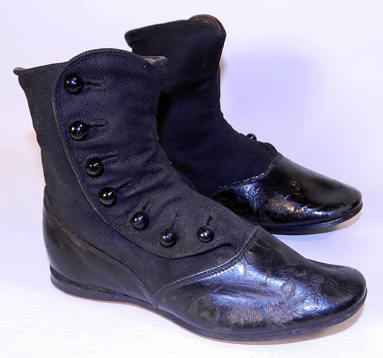 Victorian Black Wool Leather High Button Button Baby Boots Childs Shoes. They are made of a two tone black wool fabric top and black patent leather bottom shoe, with 7 black buttons down the side for closure. 