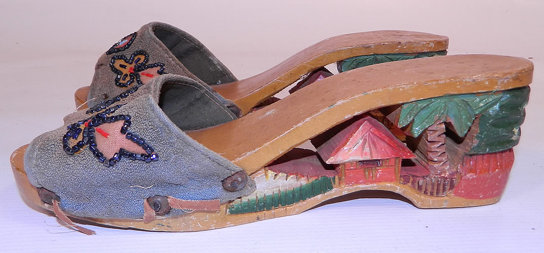 Vintage Philippines Hand Painted Carved Wooden Wedge Mules Sandal Shoes. This pair of vintage Philippines hand painted carved wooden wedge mules sandal shoes date from the 1940s. They are made of a hand painted carved wood, with a cut out tropical hut, palm tree heel and hand beaded blue fabric across the instep front vamp. 