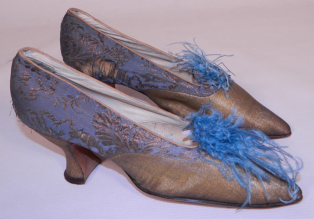 Edwardian Titanic Blue Silk Gold Lam&eacute; Damask Brocade Feather Trim Shoes. They are made of a blue silk damask, floral leaf brocade patterned gold metallic lam&eacute; fabric. These beautiful brocade fancy evening shoes have blue ostrich feather trim pompoms on the front instep vamps, a slip on style, with pointed toes and gold lam&eacute; covered French Louis XV spool heels.