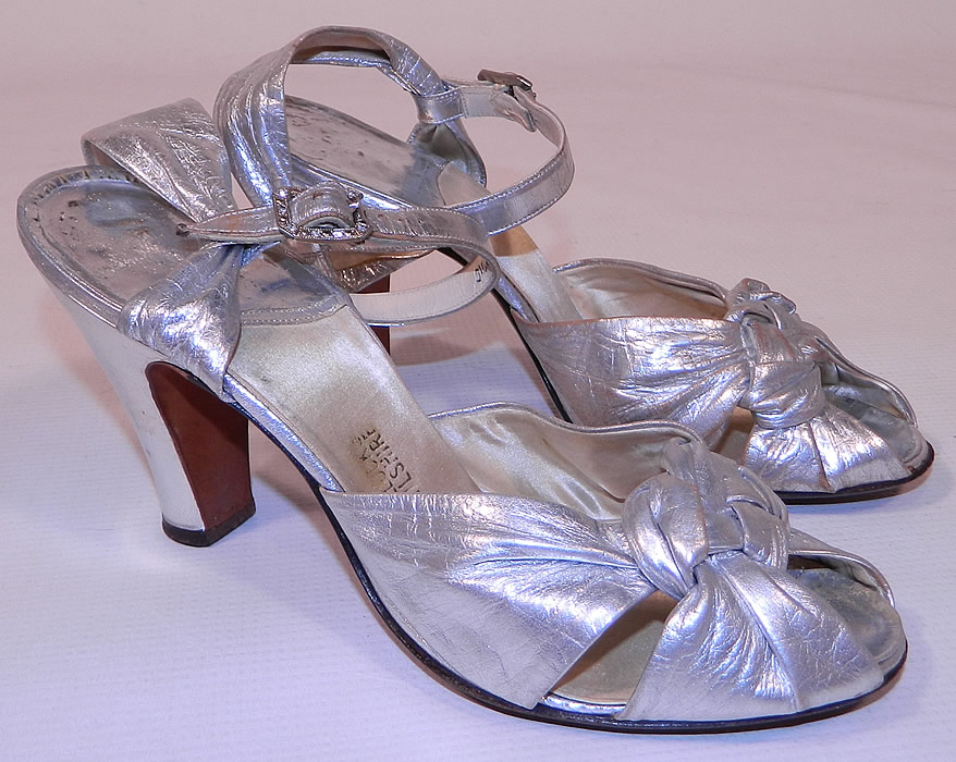 Vintage Bullock's Wilshire Silver Lam&eacute; Lame Leather Ankle Strap Evening Dance Shoes 
These elegant evening dance shoes have a decorative knotted braided designs on the front instep vamps, with an open toe, adjustable ankle straps with rhinestone buckle closures and silver leather covered modified boulevard high heels. 