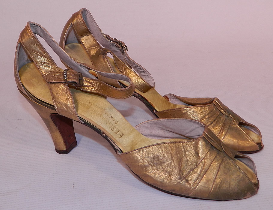 Vintage E.T. Slatter Co. Boston Label Gold Leather Ankle Strap Evening Dance Shoes
These elegant evening dance shoes have a decorative twisted knot design on the front instep vamps, with an open toe, adjustable ankle straps with rhinestone buckle closures and gold leather covered modified boulevard high heels. 