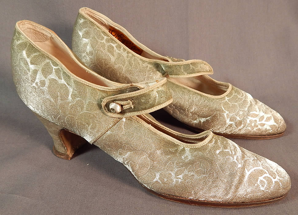 Vintage Traveler Shoe Art Deco Silver Lam&eacute; Lame Brocade Mary Jane Button Strap Shoes
This pair of vintage Traveler Shoe Art Deco silver lam&eacute; brocade Mary Jane button strap shoes date from the 1920s. They are made of a silver metallic lam&eacute; damask weave brocade fabric, with a woven floral rose leaf pattern design.