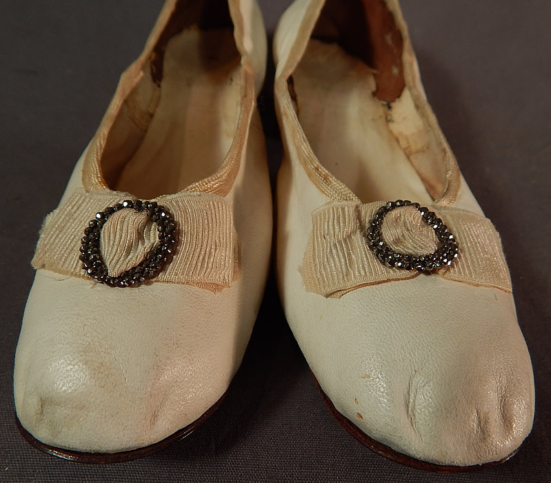 Victorian White Kid Leather Steel Cut Beaded Buckle Silk Bow Wedding Shoes
This pair of antique Victorian era white kid leather steel cut beaded buckle silk bow wedding shoes date from 1870. They are made of a white kid leather, with cream silk grosgrain bows and steel cut beaded buckle trim on the instep front vamps.