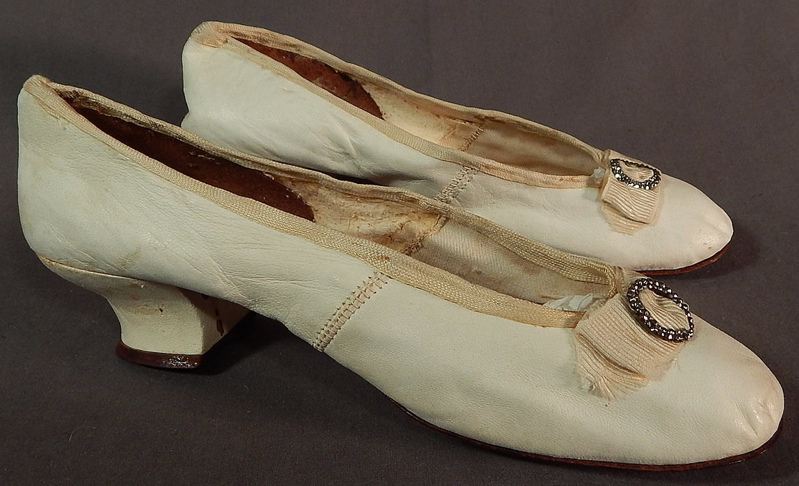 Victorian White Kid Leather Steel Cut Beaded Buckle Silk Bow Wedding Shoes
These beautiful bridal wedding shoes have a slip on slipper style, with a slight crooked sole, leather covered Louis XV French heel, rounded toes and cream silk braided trim edging along the top. 