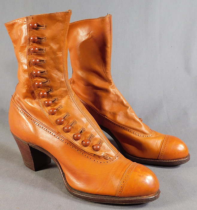 Edwardian Vintage Unworn Womens Tan Leather High Top Button Boots
This pair of antique Edwardian era unworn womens tan leather high top button boots date from 1910. They are made of light brown color tan leather with decorative punch work designs on the shoe.