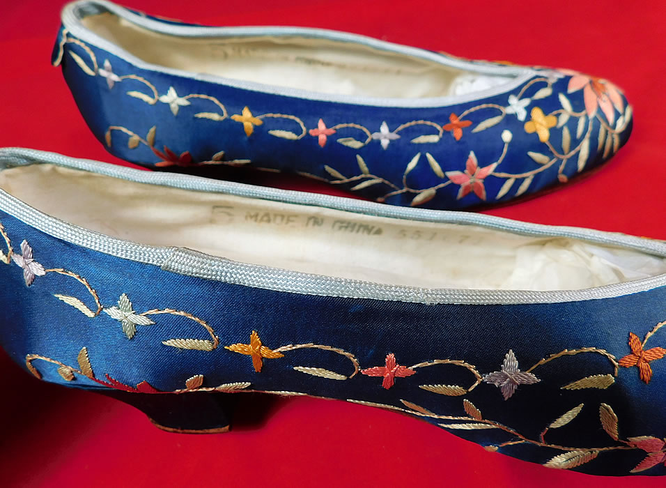 Antique Chinese Blue Silk Colorful Floral Lotus Embroidered Heel Shoes
. These slipper style slip-on shoes have hard leather bottom soles, blue silk covered heels and are fully lined in linen, with a "Made in China" size 5 ink stamp label inside. The shoes measure 9 1/2 inches long, 2 1/2 inches wide, with 1 1/2 inch high heels and are approximately a size 6 narrow width.