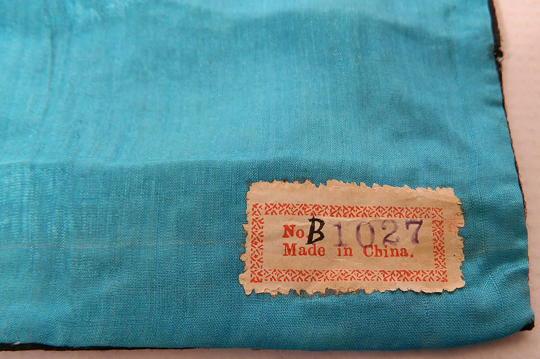 Antique Chinese Silver Couching Paradise Flycatcher Bird 9th Rank Badge Pair label close up.It is fully lined backed inside in blue silk, with a "Made in China" old paper label tag. Each badge measures 8 by 8 inches and is in good unused condition. This is a wonderful piece of antique Chinese textile art! 