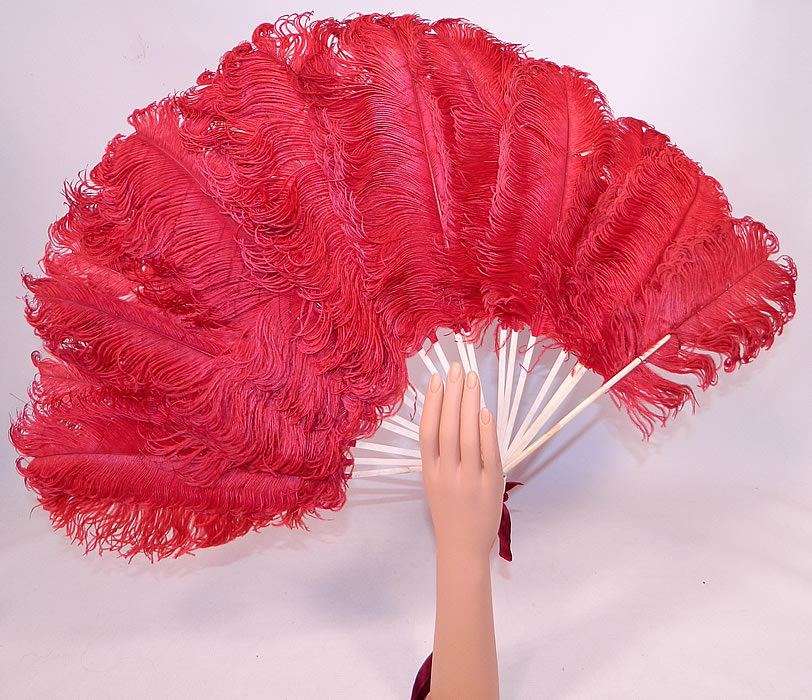 Antique Edwardian Red Ostrich Feather Folding Fan Velvet Ribbon
It is made of large fluffy dyed red ostrich feather plumes. There are bleached white bone sticks and guards with a loop, mother of pearl rivet and burgundy red silk velvet ribbon tie on the bottom for carrying. 