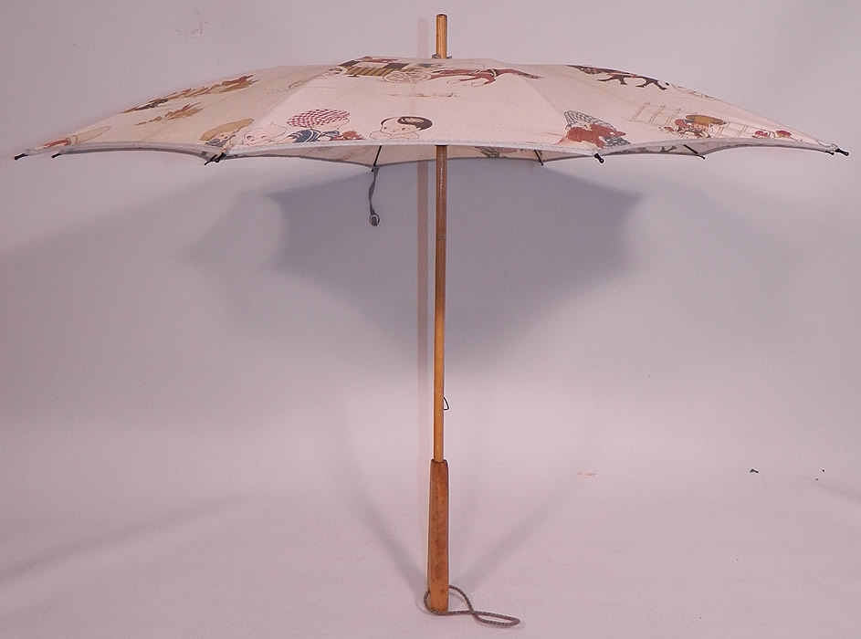 Vintage Chloe Preston Childrens Kewpie Illustration Print Linen Parasol
There is a wooden handle and finial top with blue gathered scrunchie fabric trim, button strap closure and blue rope strap attached to the bottom handle for carrying.